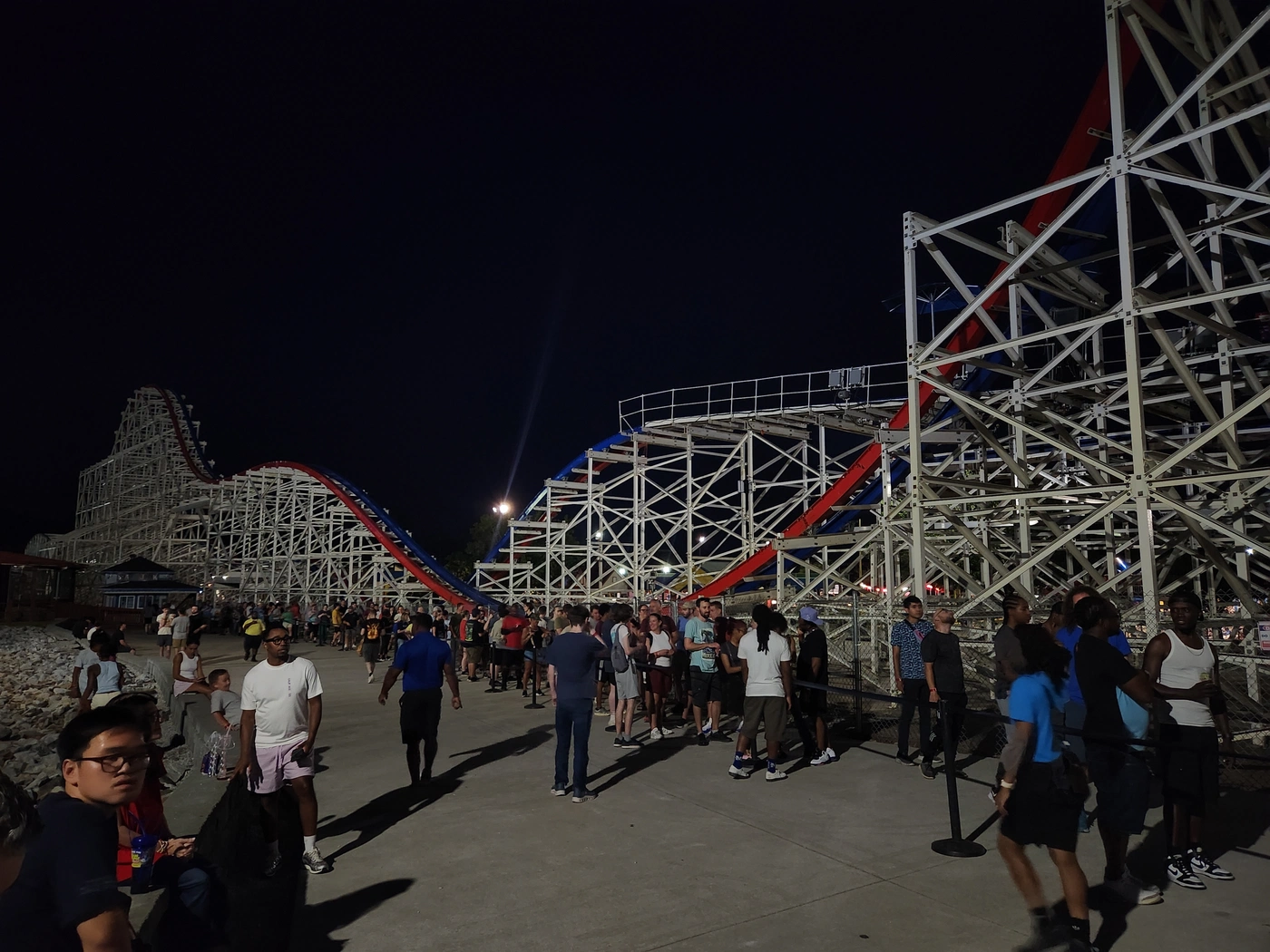 A crowd of people waiting in line to ride ArieForce One at night